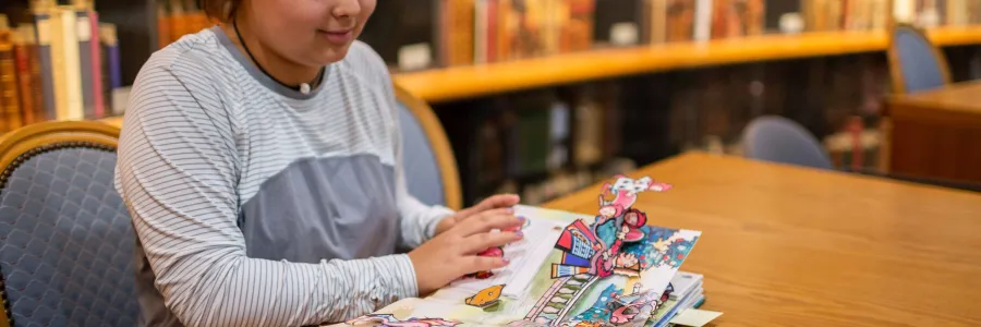 A student looks at a pop-up book