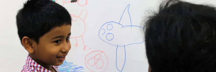 Photo of a young boy drawing on a whiteboard