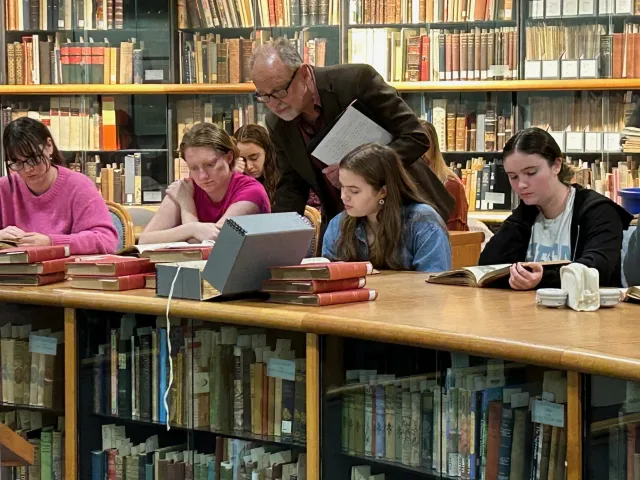 Prof. West and students look at books